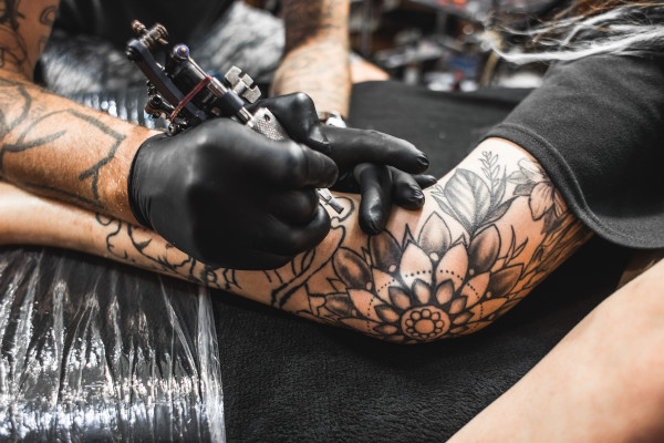 Tattoo wird gestochen, Kunde hat Schmerzen